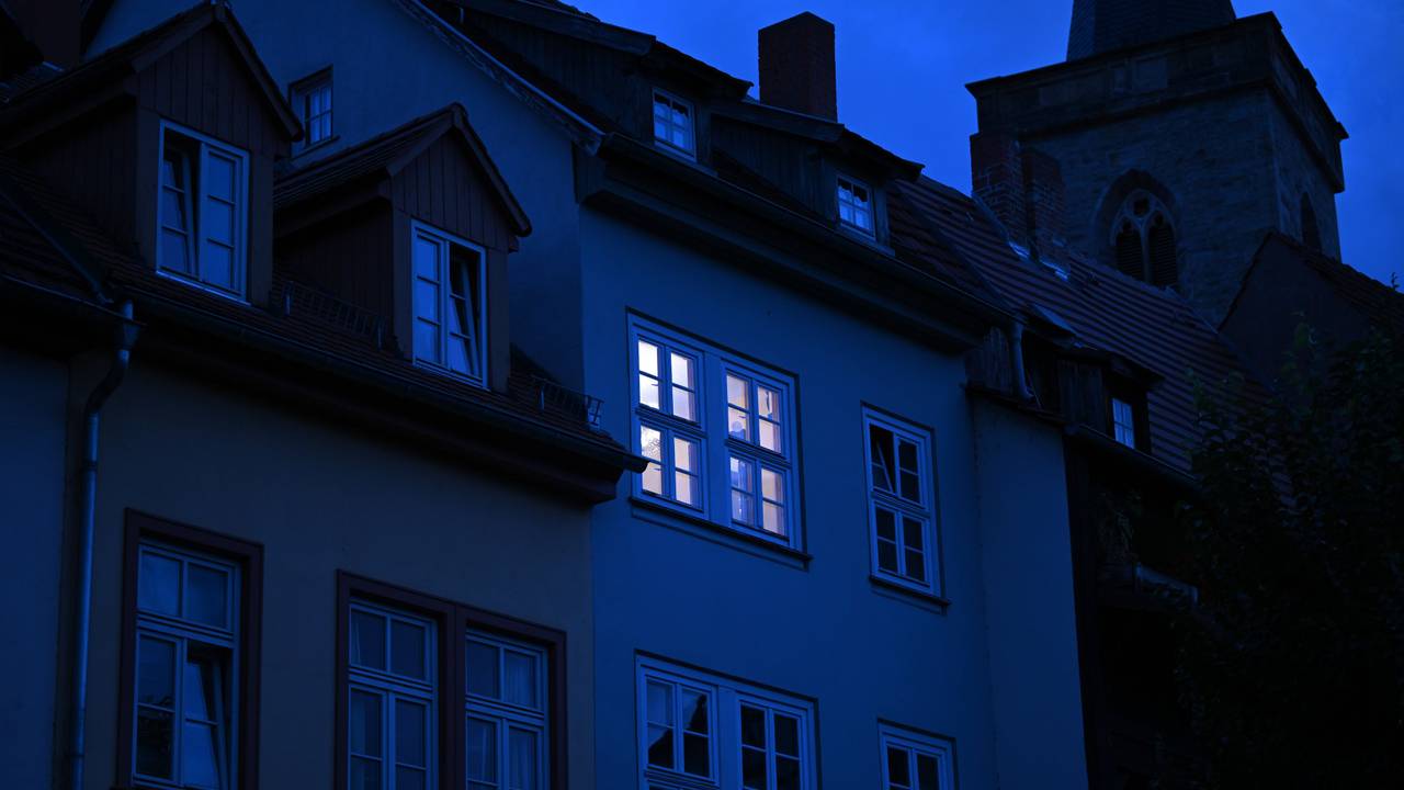 Dieses undatierte Symbolbild zeigt ein hell erleuchtetes Wohnungsfenster im Morgengrauen.