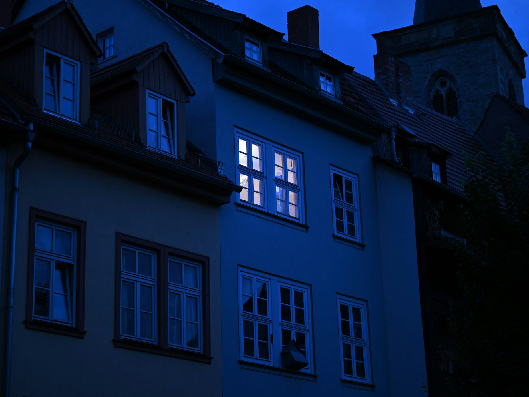 Dieses undatierte Symbolbild zeigt ein hell erleuchtetes Wohnungsfenster im Morgengrauen.