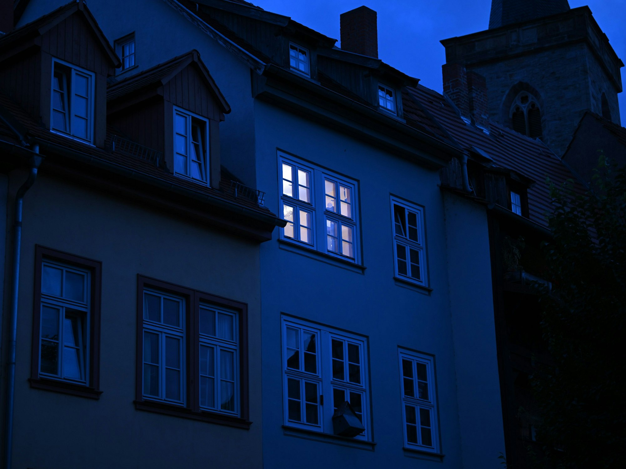 Dieses undatierte Symbolbild zeigt ein hell erleuchtetes Wohnungsfenster im Morgengrauen.