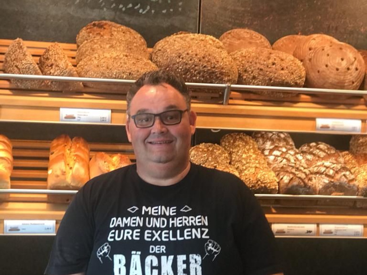 Bäcker Gudio Boveleth steht in seiner Bäckerei vor einem Brotregal.