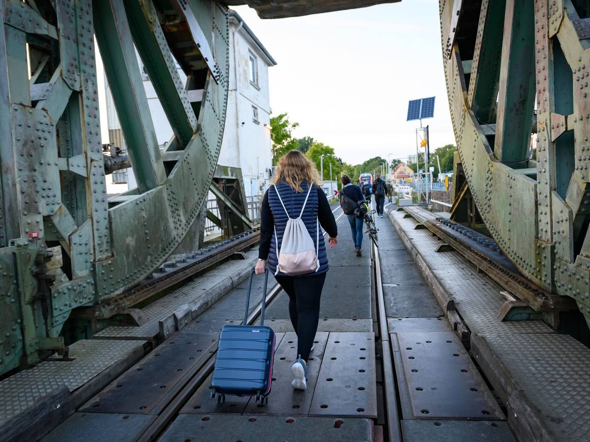 Eine Frau läuft mit einem Koffer über die Lindaunisbrücke. Normalerweise fahren Züge über die Schleibrücke bei Lindaunis. Seit Mitte September aber heißt es für Fahrgäste: Austeigen und zu Fuß die Schlei passieren.