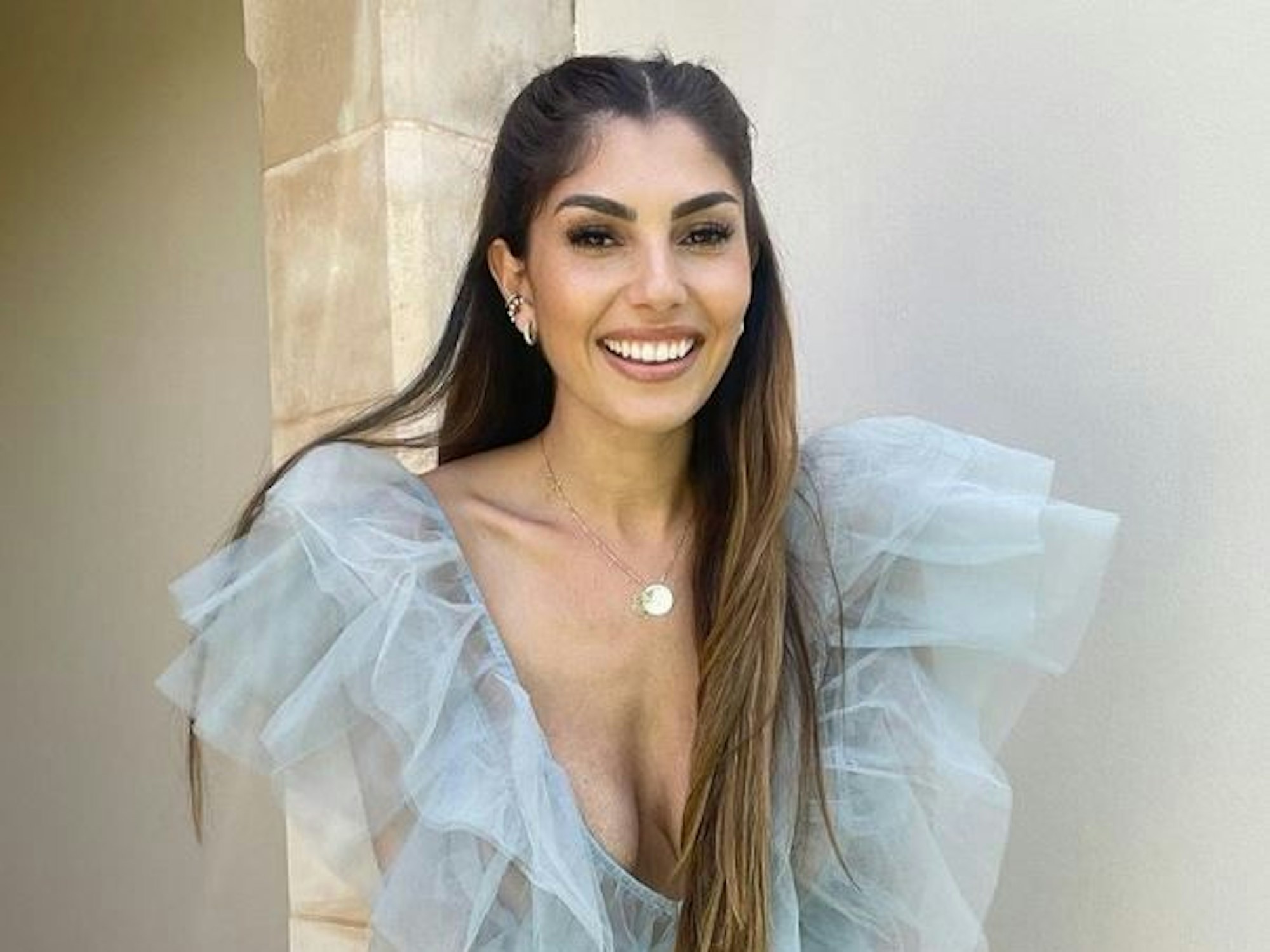 Yeliz Koc lacht in einem durchsichtigen, blauen Kleid in die Kamera.