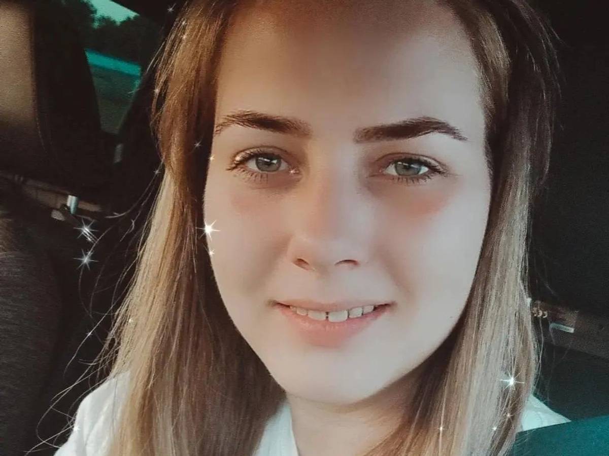 Sarafina posiert für ein Selfie im Auto. Sie trägt ein weißes Shirt und lächelt in die Kamera.