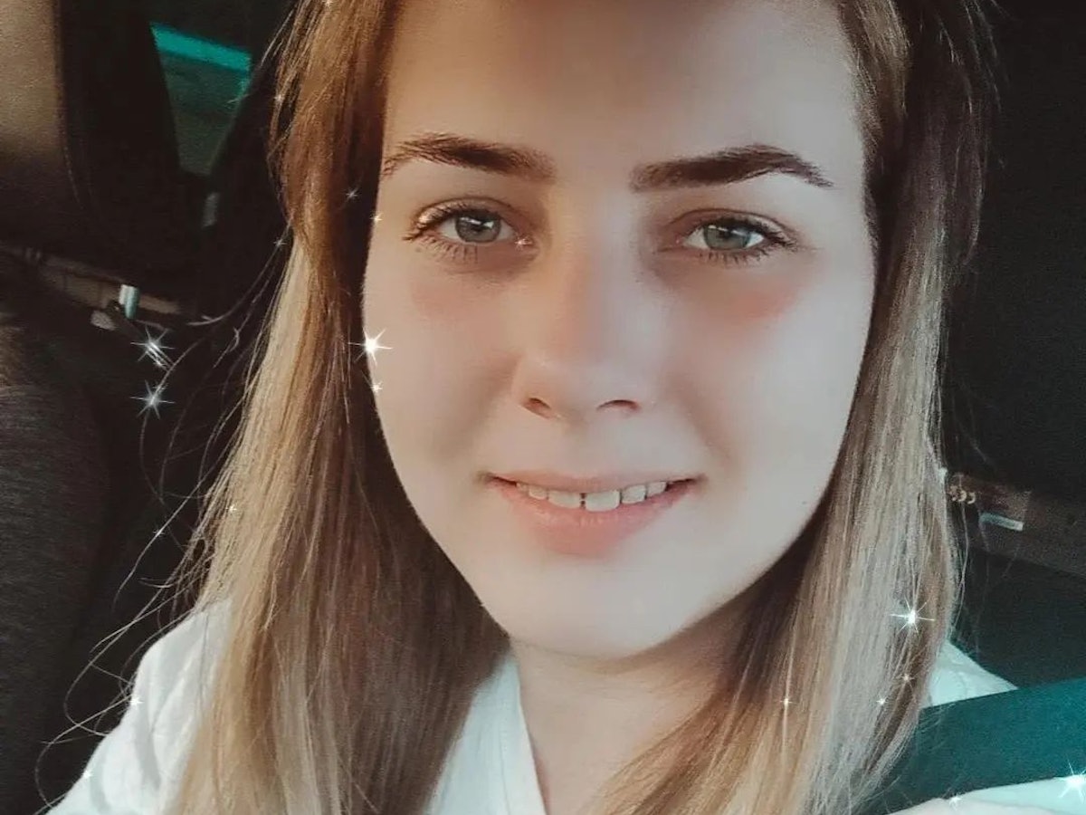 Sarafina posiert für ein Selfie im Auto. Sie trägt ein weißes Shirt und lächelt in die Kamera.