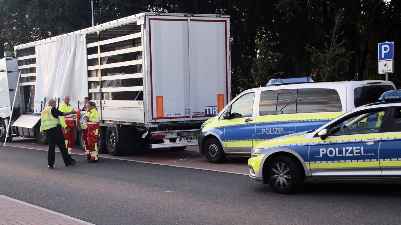 Ein Polizist und Mitarbeiter des Rettungsdienstes diskutieren vor einem Sattelauflieger.