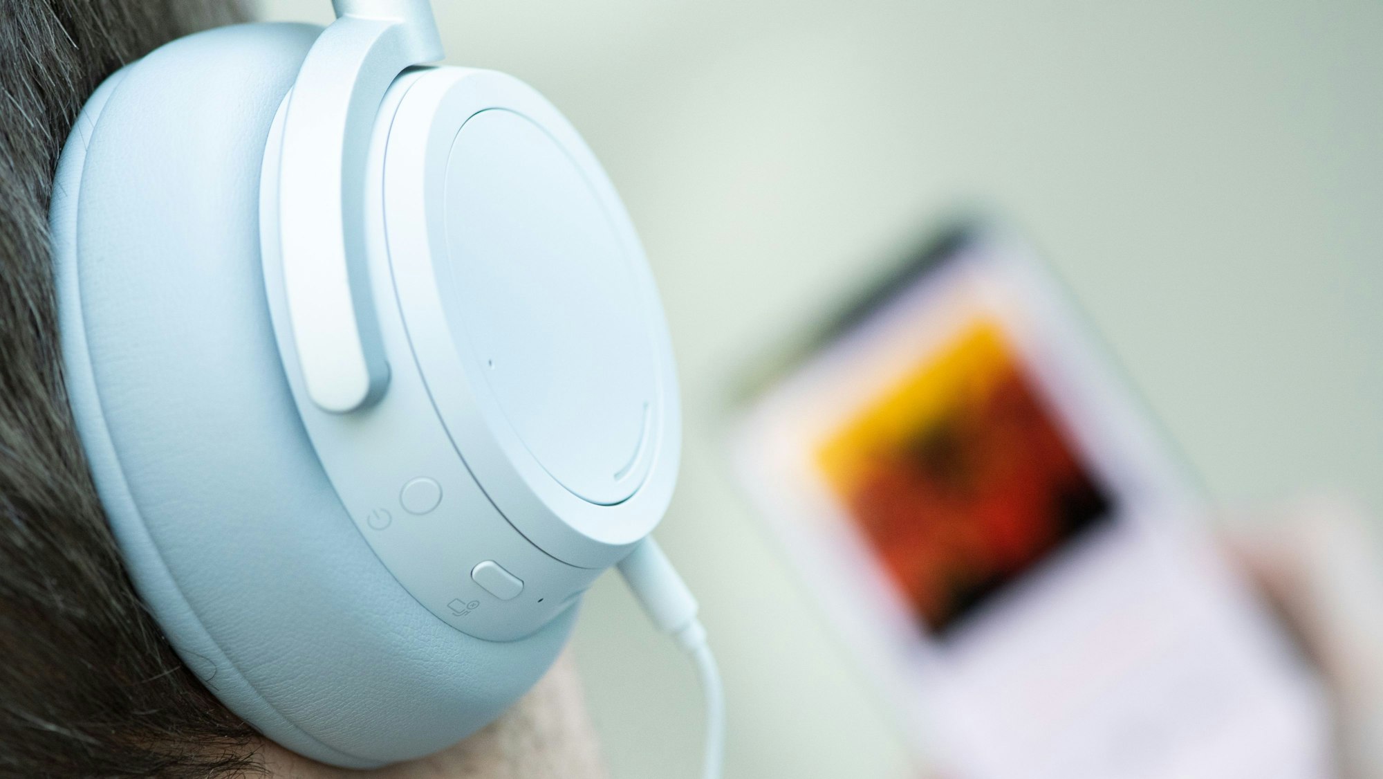 Auf dem Symbolfoto vom 2. April 2019 hat ein junger Mann Kopfhörer aufgesetzt und hört Musik von seinem Smartphone.