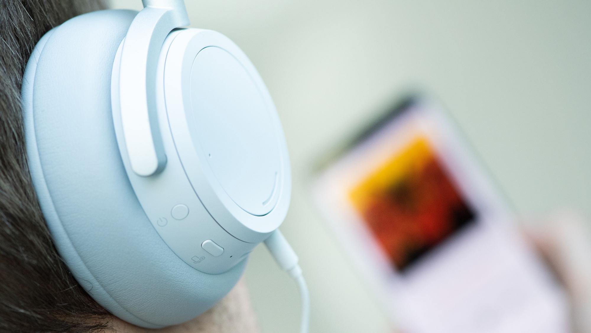 Auf dem Symbolfoto vom 2. April 2019 hat ein junger Mann Kopfhörer aufgesetzt und hört Musik von seinem Smartphone.