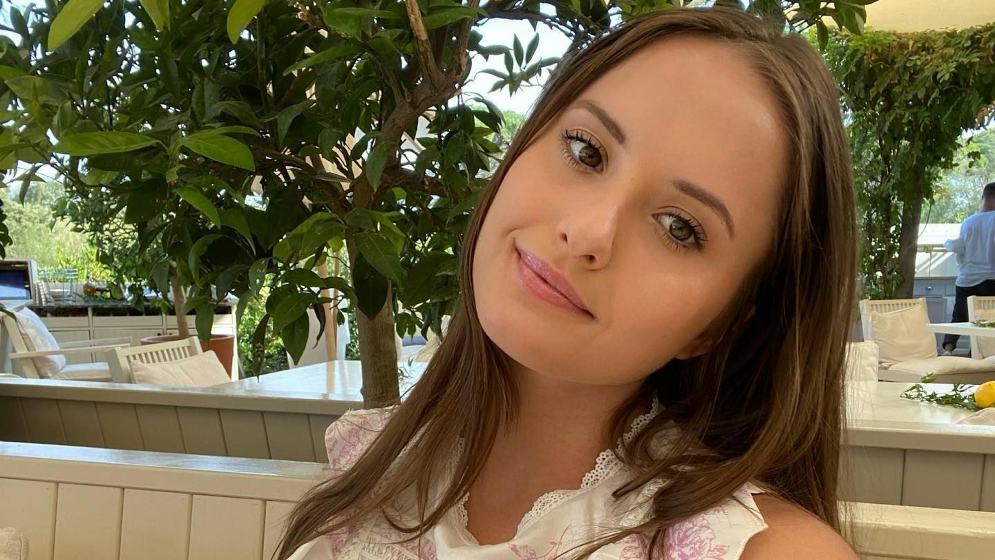 Davina posiert für ein Selfie. Sie trägt eine weiße Bluse.