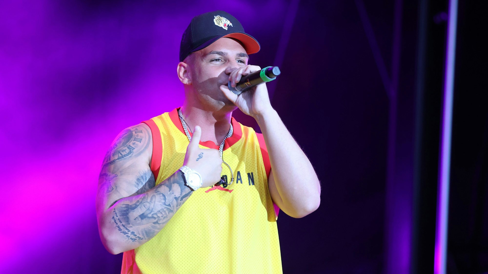 Der deutsche Sänger Pietro Lombardi tritt bei einem Sommer Open Air Konzert auf. Er trägt ein gelbes Tanktop und eine schwarze Kappe.