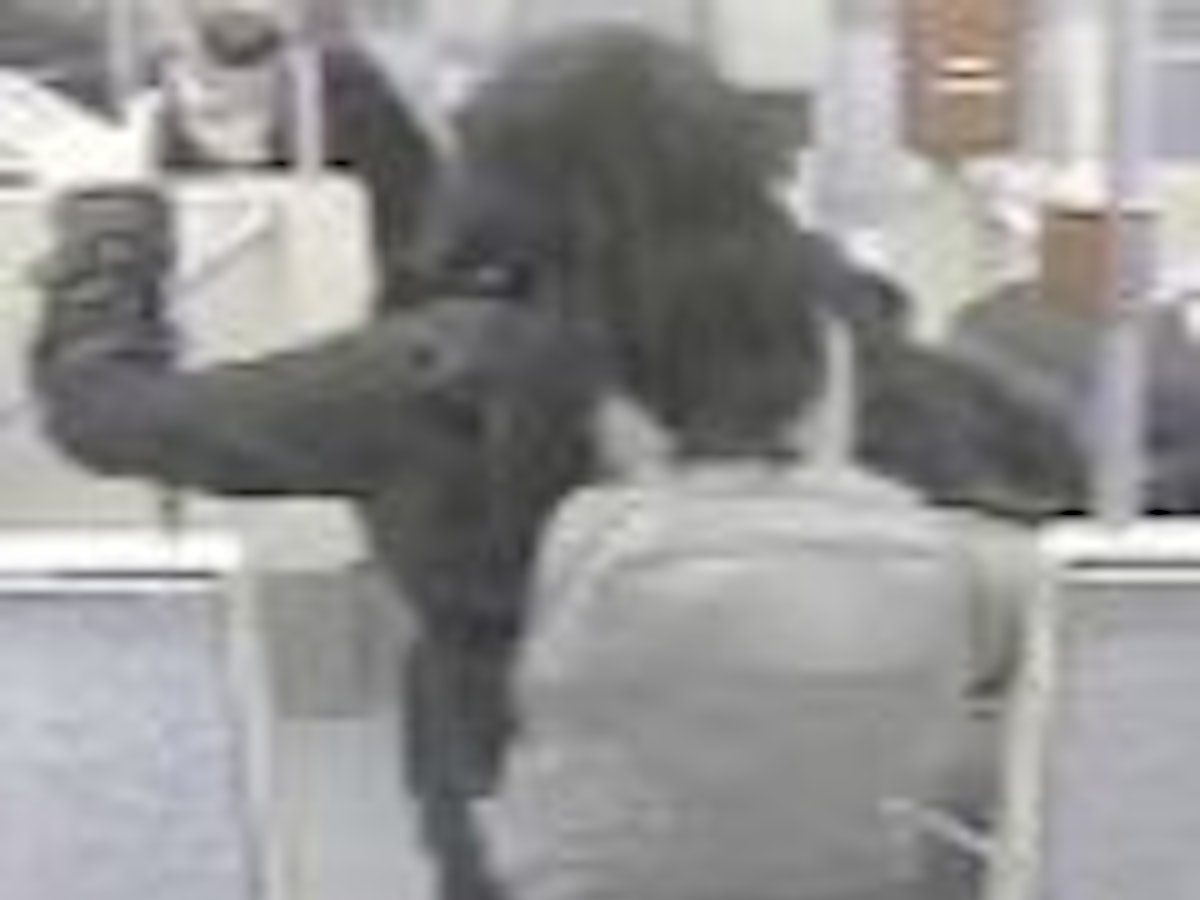 Das Fahndungsfoto zeigt eine Frau von hinten, die im März 2022 zwei Frauen fremdenfeindlich beleidigt und sie mit einem Rucksack attackiert haben soll.