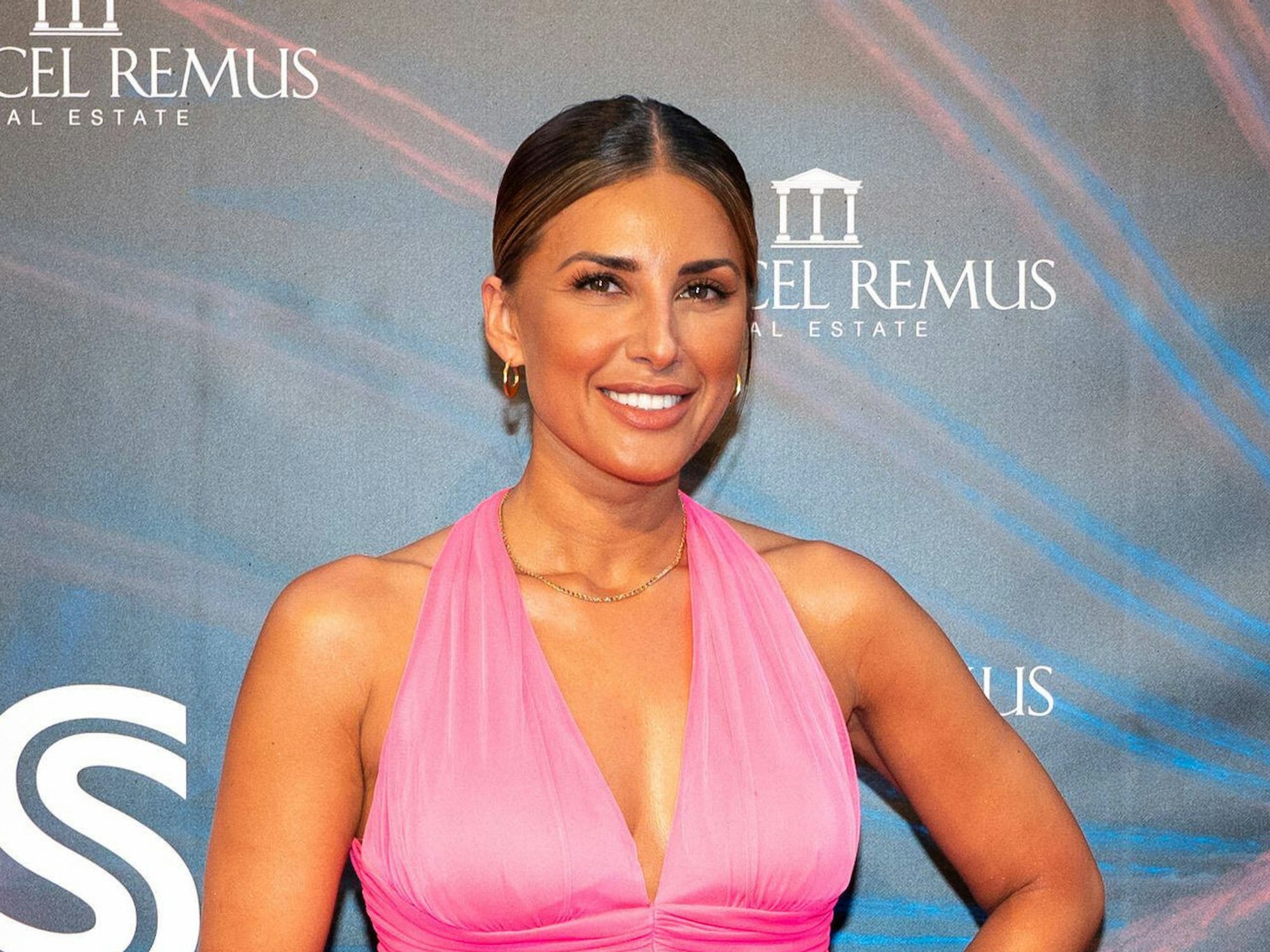 Jana Azizi steht im pinken Kleid auf dem Roten Teppich.