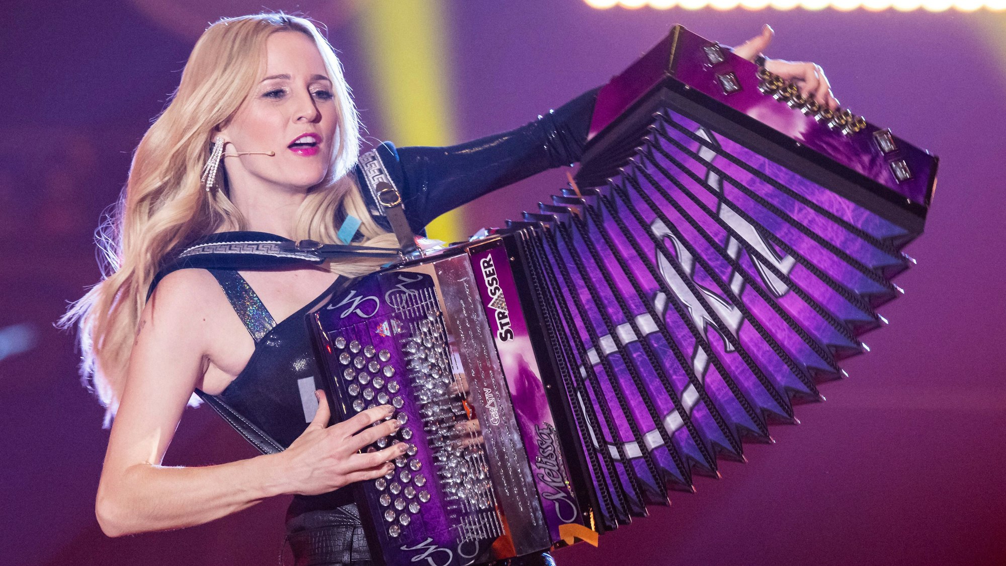 Melissa Naschenweng steht während einer TV-Aufzeichnung auf der Bühne. Sie spielt auf einem Akkordeon.