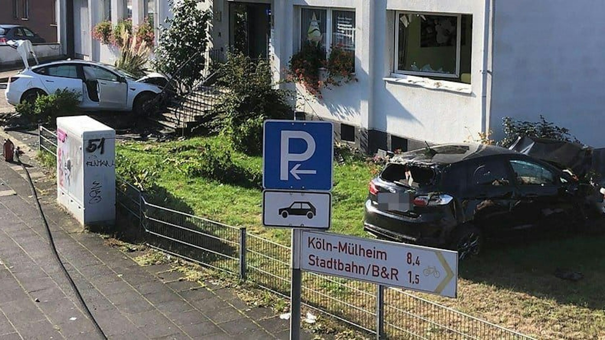 Zwei kaputte Autos liegen in einem Garten in Leverkusen-Schlebusch.