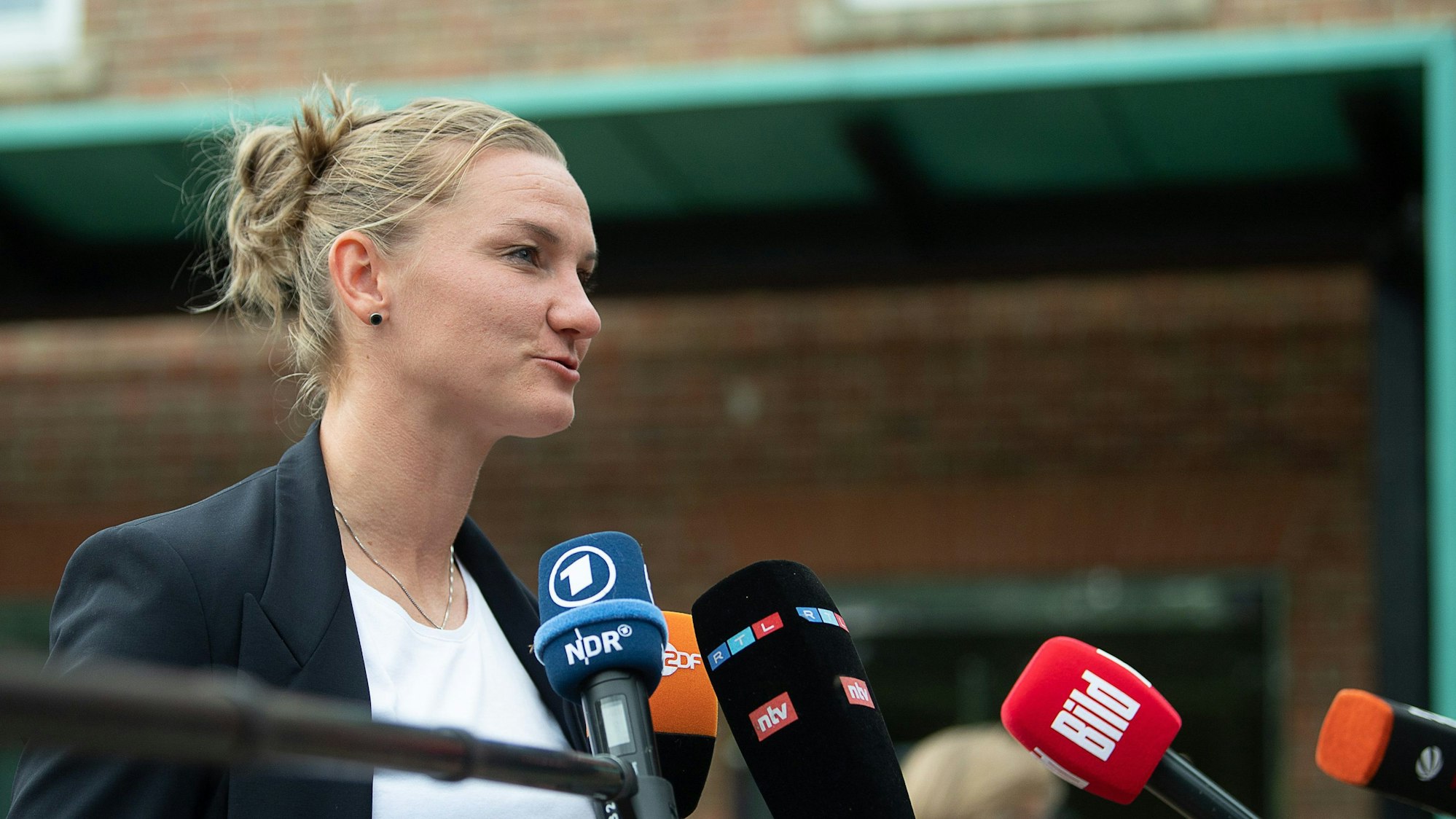 Alexandra Popp steht vor Mikrofonen und beantwortet Fragen der Journalisten.