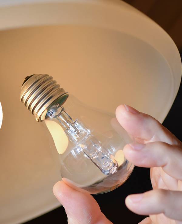 An einer Deckenleuchte wird eine Halogenlampe (r) gegen eine energiesparende LED-Lampe ausgewechselt.