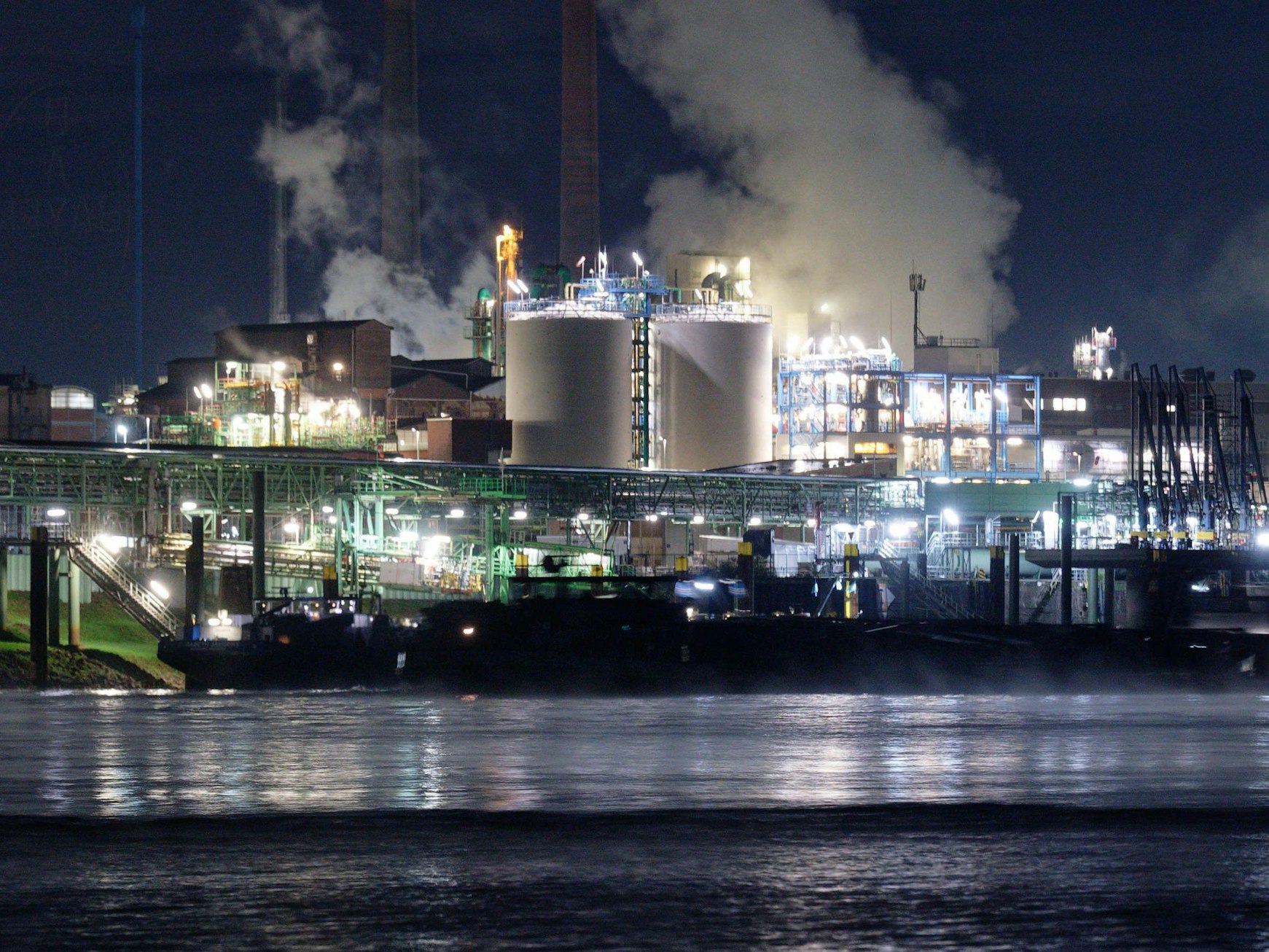 Die Lichter des Chemparks in Leverkusen spiegeln sich im Wasser des Rheins.