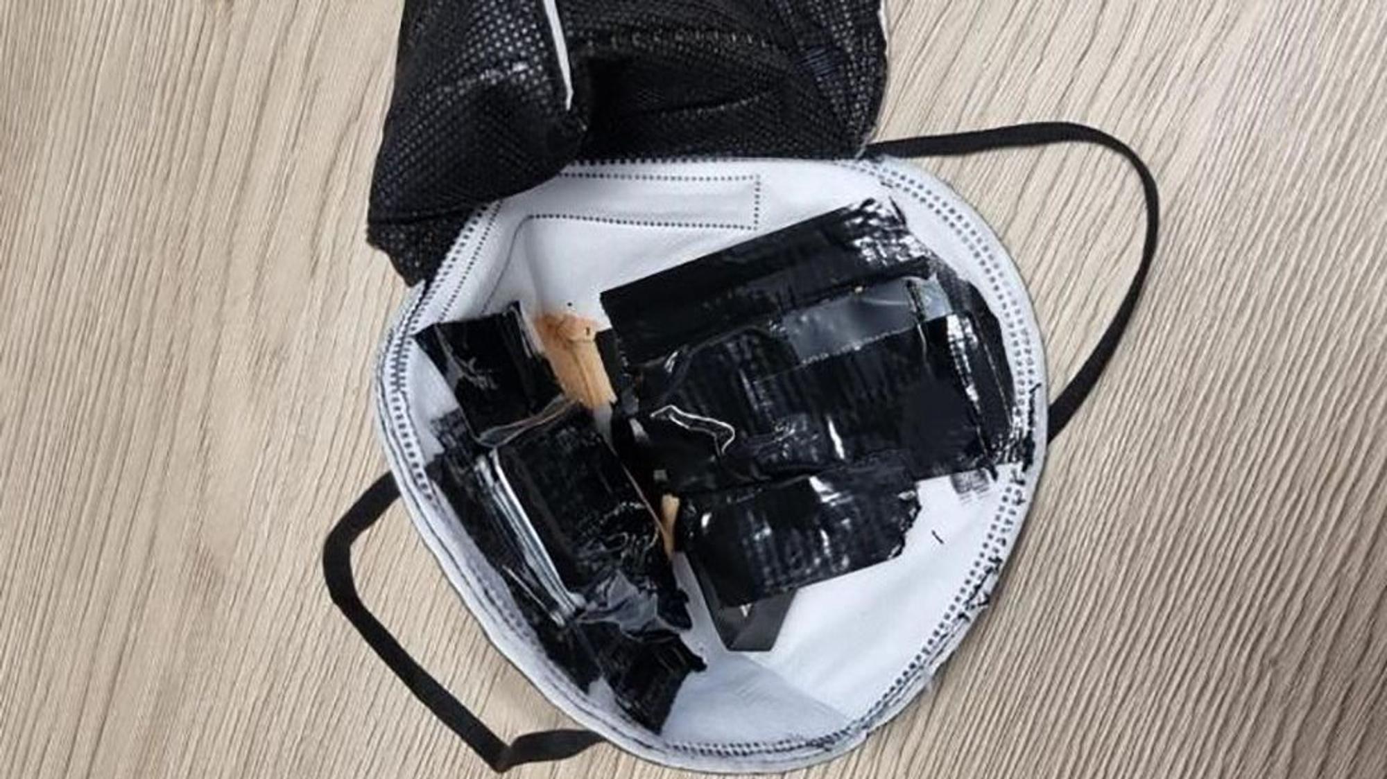 Eine eingenähte Kamera in einer FFP2-Maske liegt auf einem Tisch des TÜV Süd (undatierte Aufnahme). Sie war bei einer theoretischen Führerscheinprüfung entdeckt worden. Einen ähnlichen Betrugsfall gab es jetzt in Bergheim.