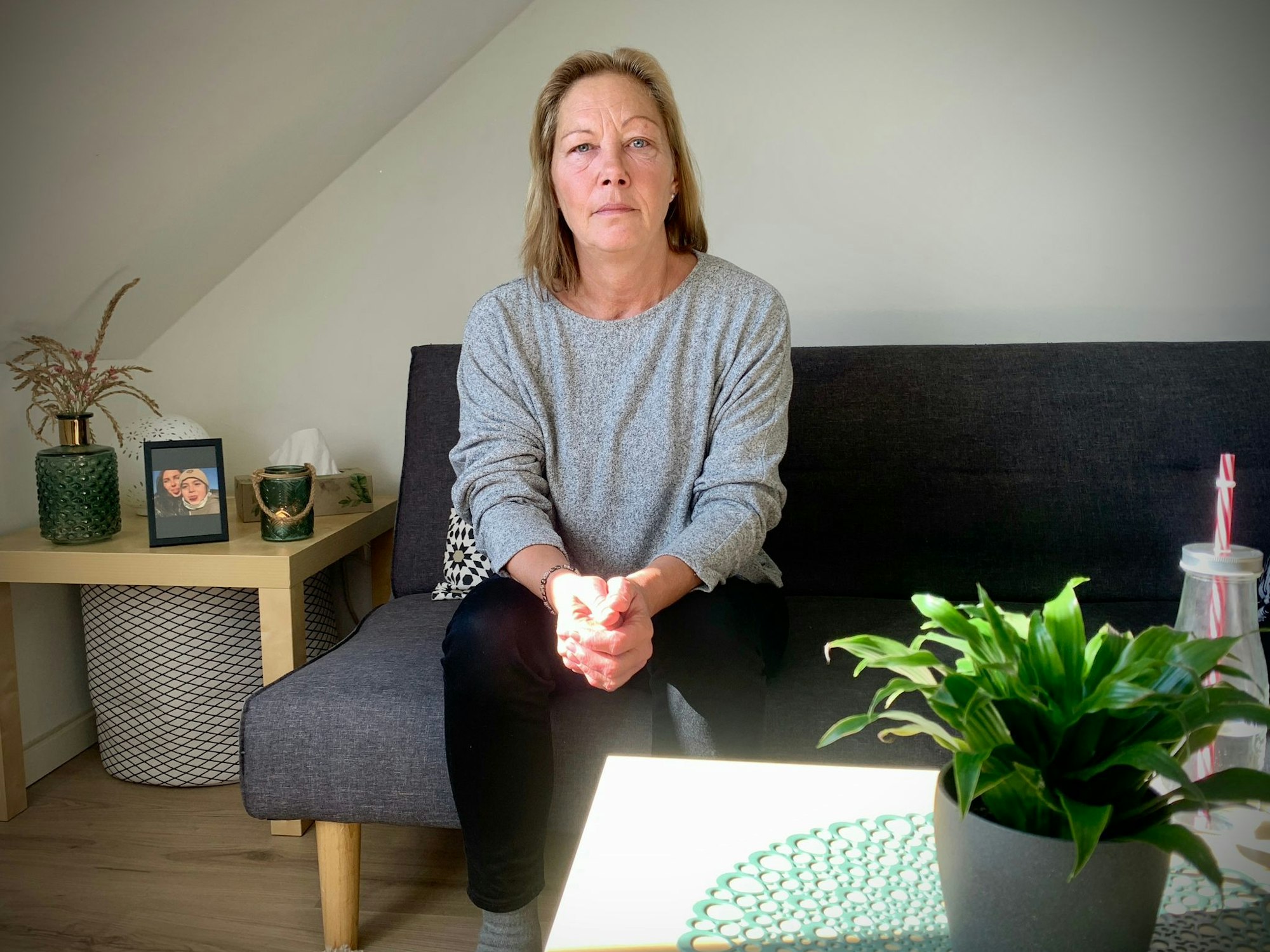 Deryas Mutter Rosi sitzt auf dem Sofa und schaut in die Kamera.