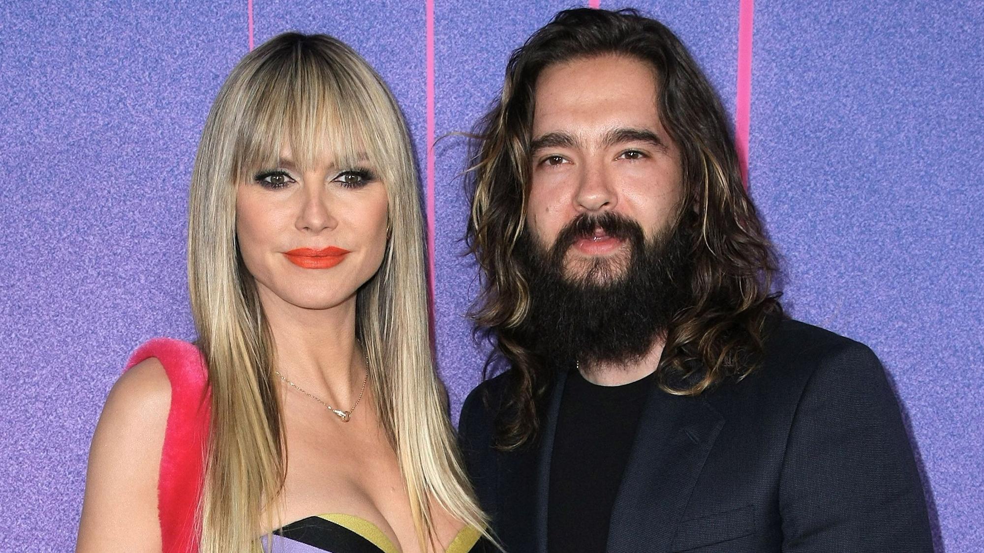 Heidi Klum und Tom Kaulitz posieren gemeinsam für die Kameras. Sie trägt ein mehrfarbiges Kleid, er ein schwarzes Shirt mit dunklem Jackett.