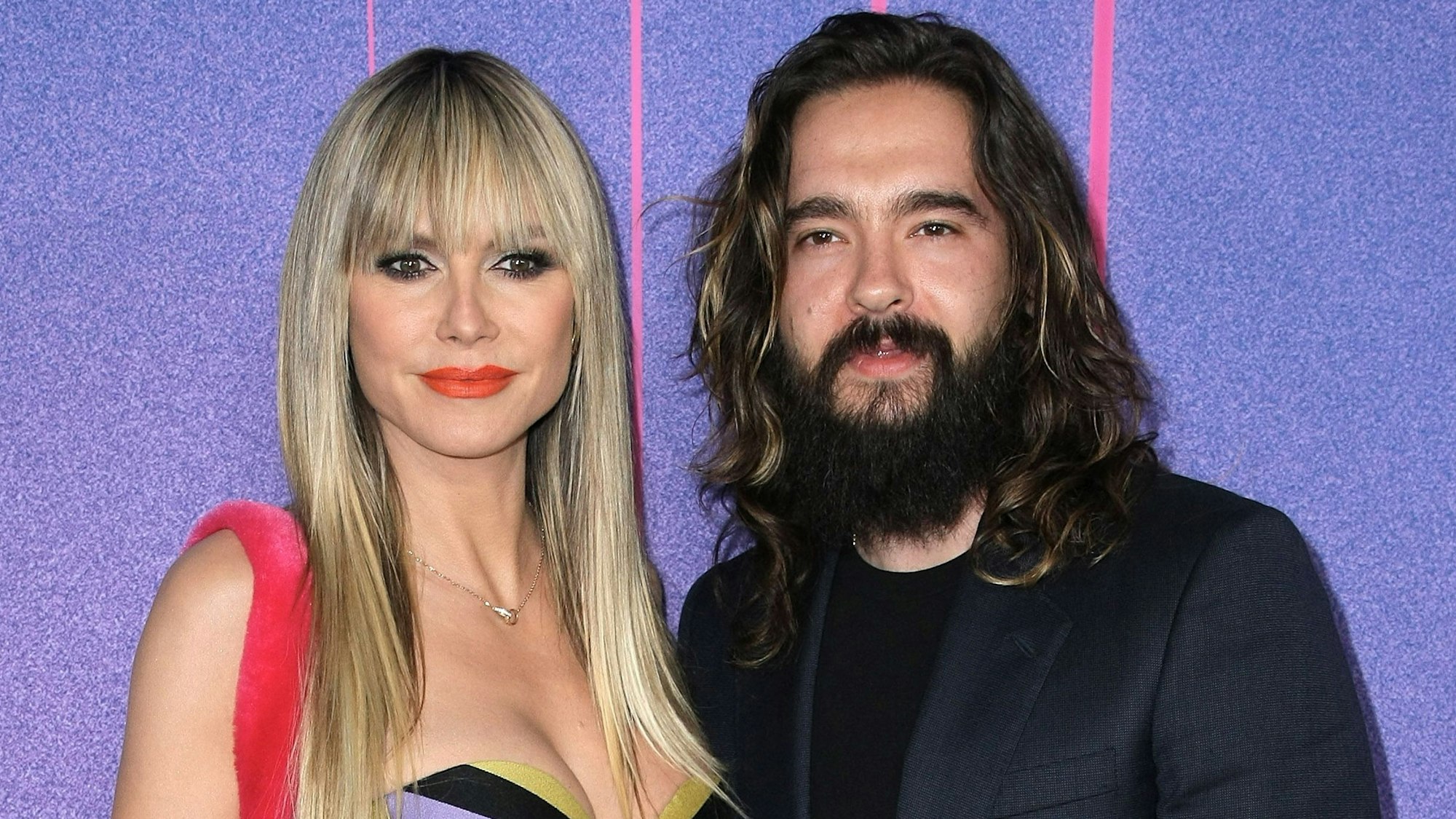 Heidi Klum und Tom Kaulitz posieren gemeinsam für die Kameras. Sie trägt ein mehrfarbiges Kleid, er ein schwarzes Shirt mit dunklem Jackett.