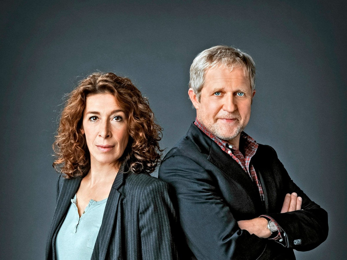 Adele Neuhauser und Harald Krassnitzer stehen Rücken an Rücken und blicken in die Kamera.