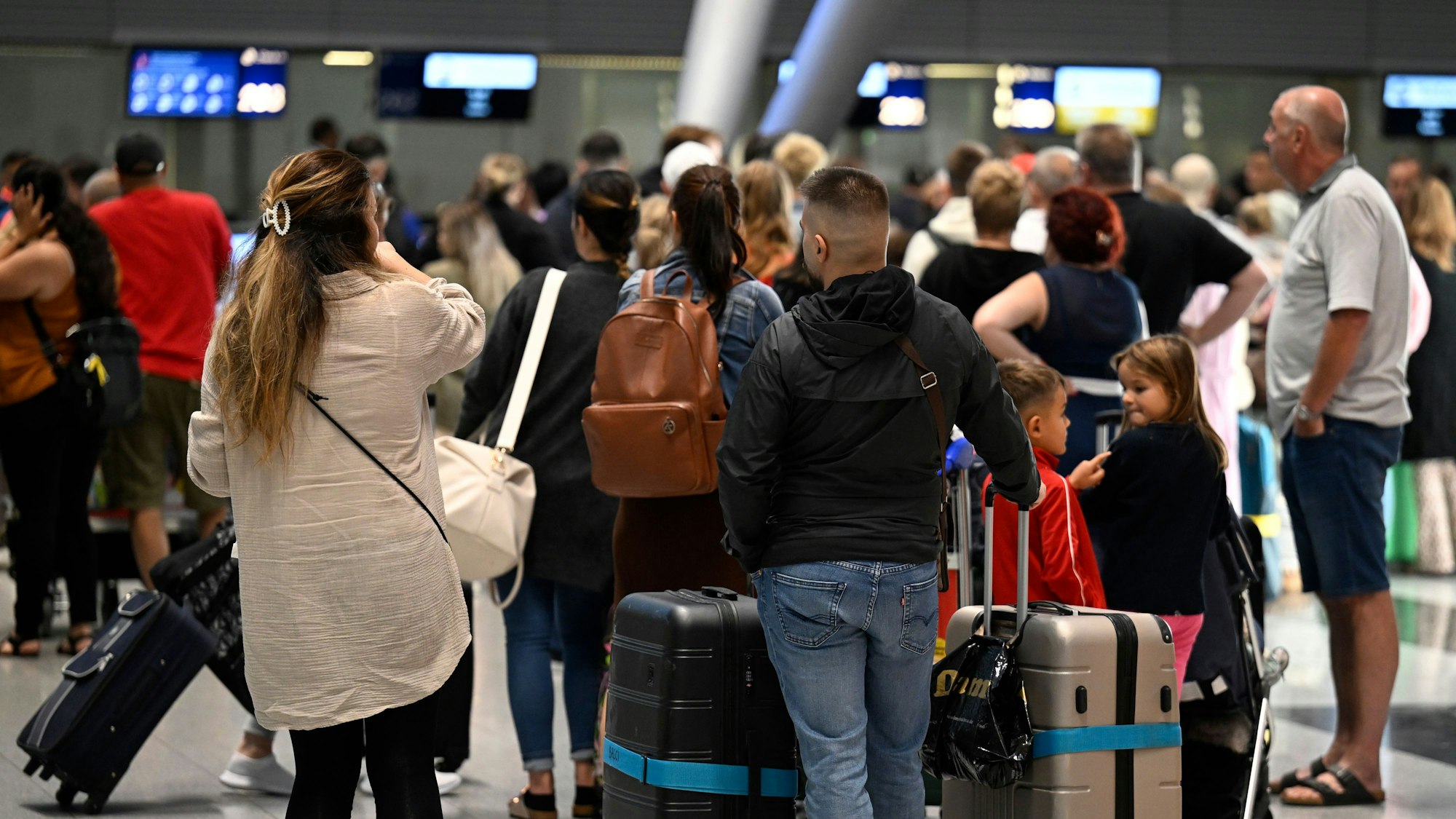 Reisende stehen in Schlangen vor den Check-In-Schaltern im Terminal.