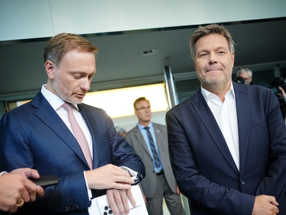 Christian Lindner (FDP, l), Bundesminister der Finanzen, blickt neben Robert Habeck (Bündnis 90/Die Grünen), Bundesminister für Wirtschaft und Klimaschutz, zu Beginn der Pressekonferenz zur Vorstellung der Pläne der Bundesregierung zur Energieversorgung und Preisbegrenzung für Gas auf die Uhr.