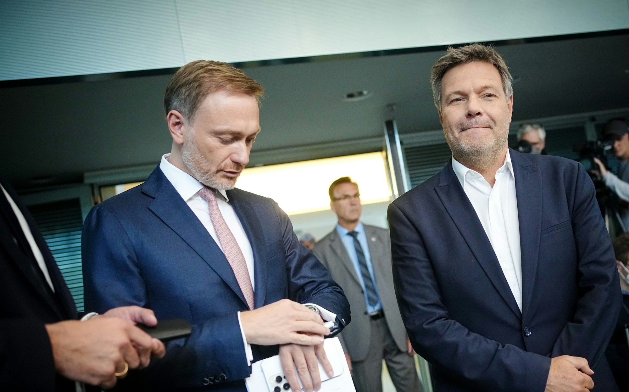 Christian Lindner (FDP, l), Bundesminister der Finanzen, blickt neben Robert Habeck (Bündnis 90/Die Grünen), Bundesminister für Wirtschaft und Klimaschutz, zu Beginn der Pressekonferenz zur Vorstellung der Pläne der Bundesregierung zur Energieversorgung und Preisbegrenzung für Gas auf die Uhr.