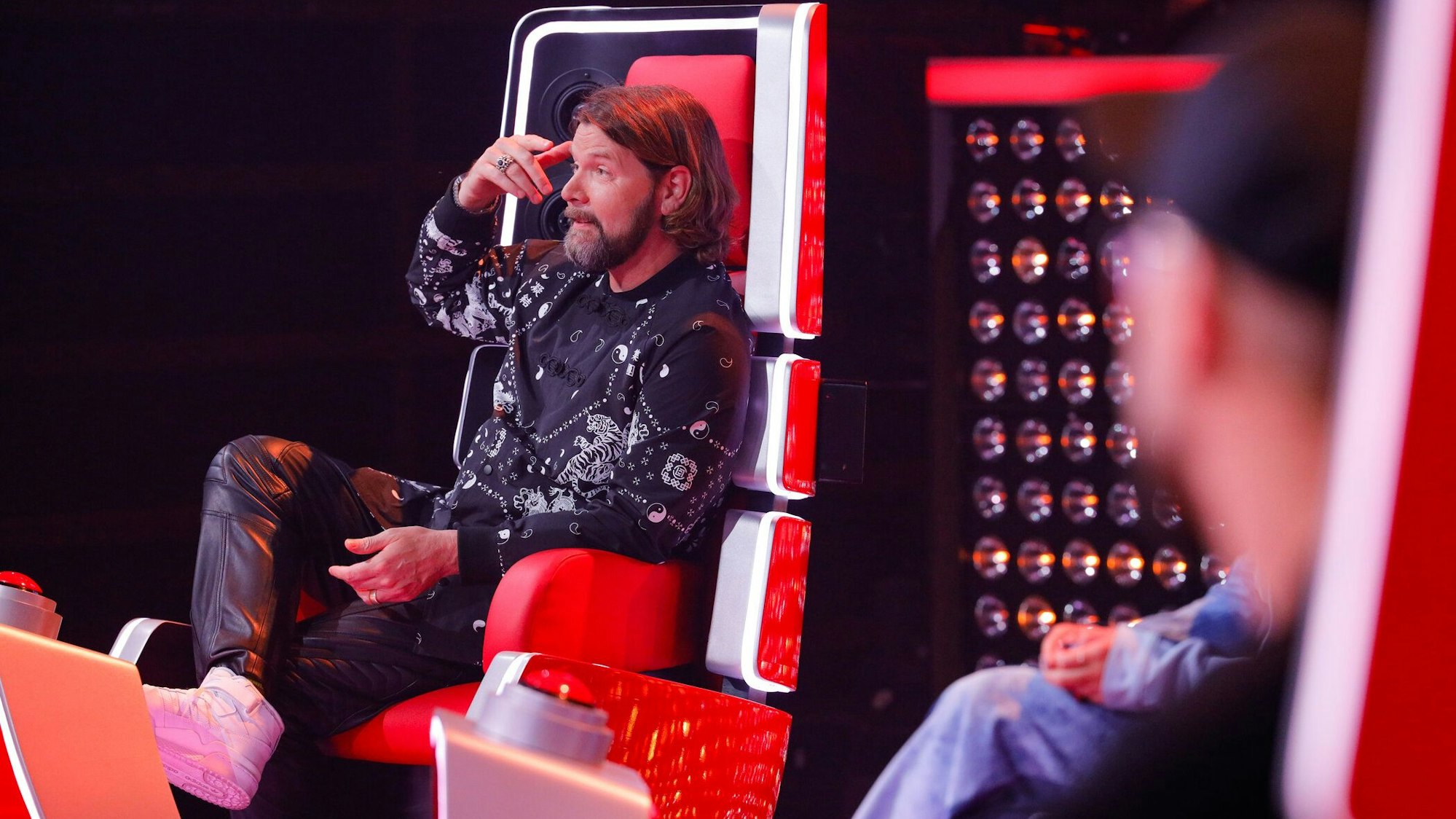 Rea Garvey sitzt bei „The Voice of Germany“ in seinem Coach-Sessel und fasst sich mit der Hand an den Kopf.