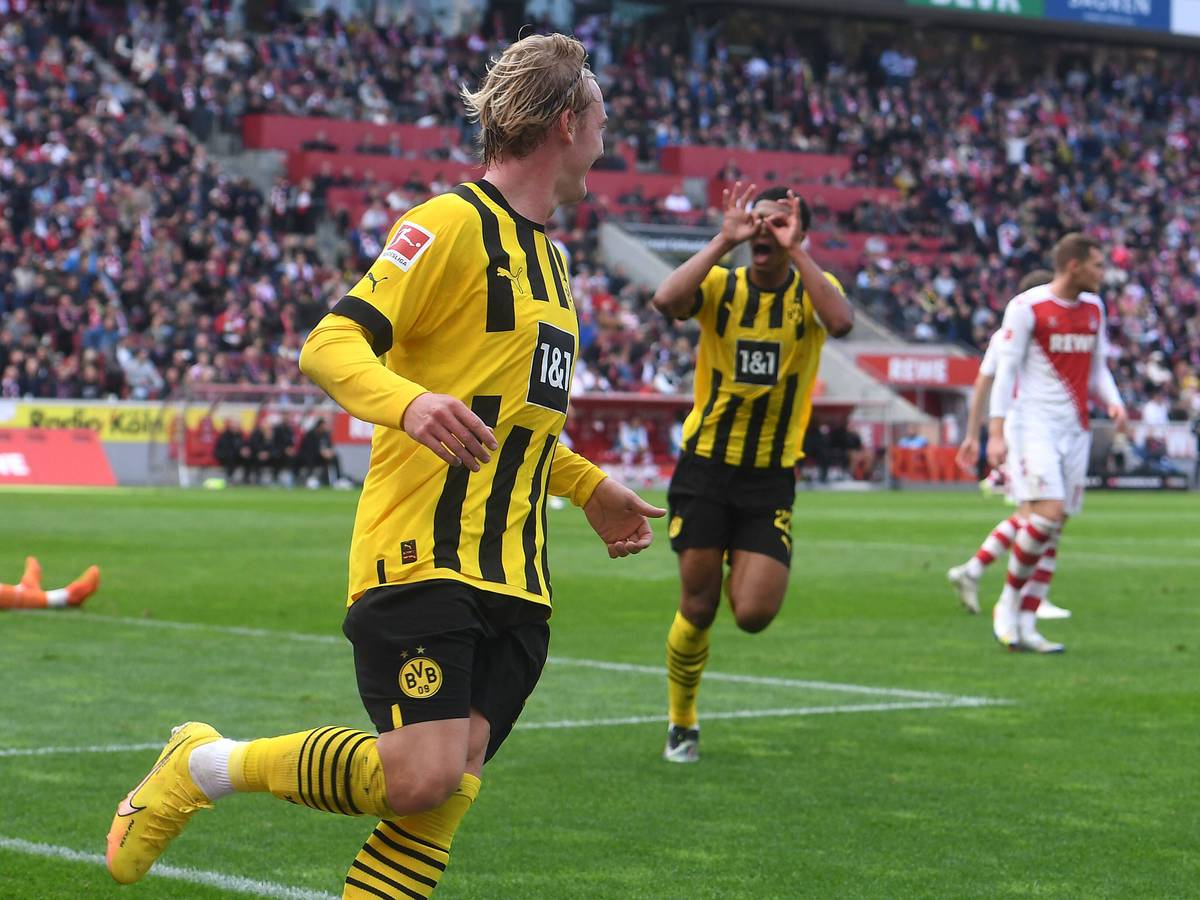 Julian Brandt (v.) feiert sein Tor zum 1:0 für Borussia Dortmund beim 1. FC Köln, Jude Bellingham zelebriert die Führung mit dem Modeste-Jubel.