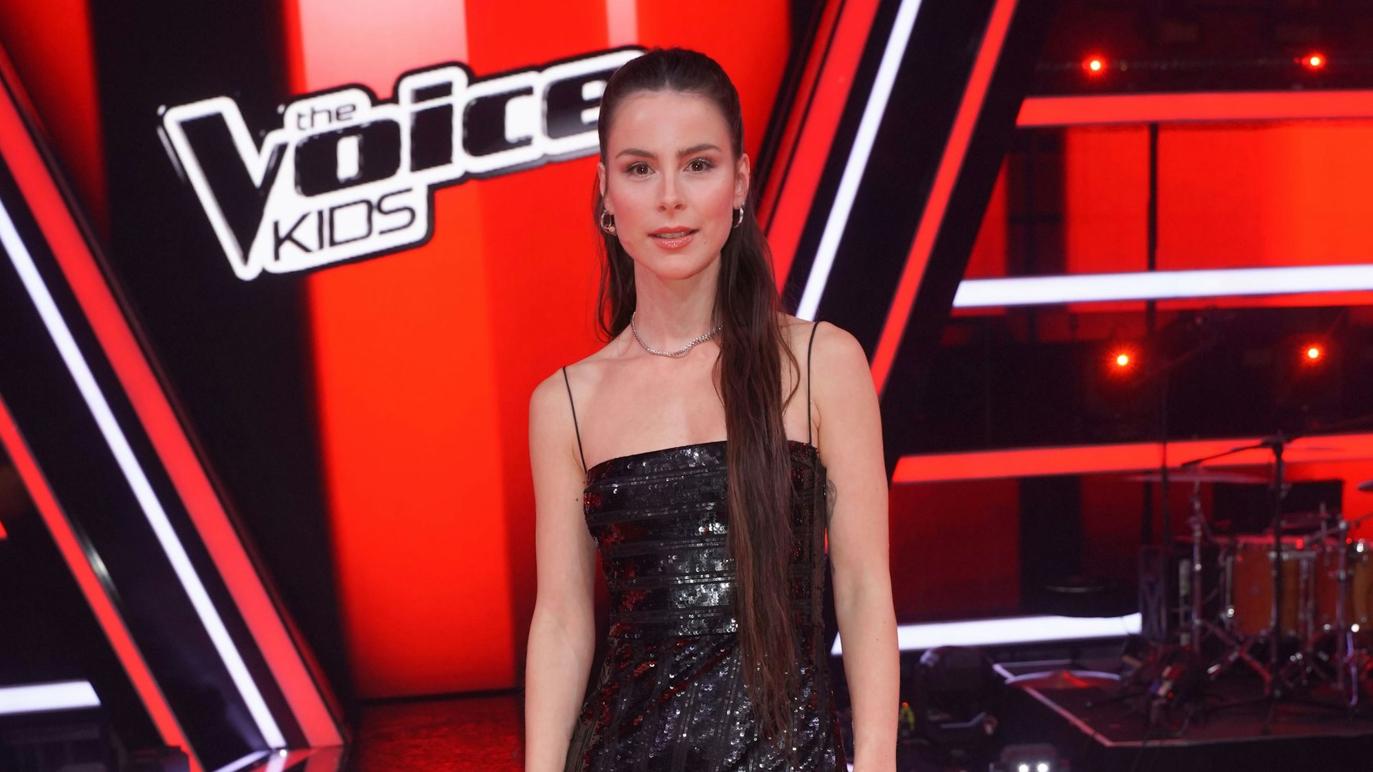 Lena trägt ein schwarzes Abendkleid. Ihre Haare sind am Hinterkopf zusammengesteckt.