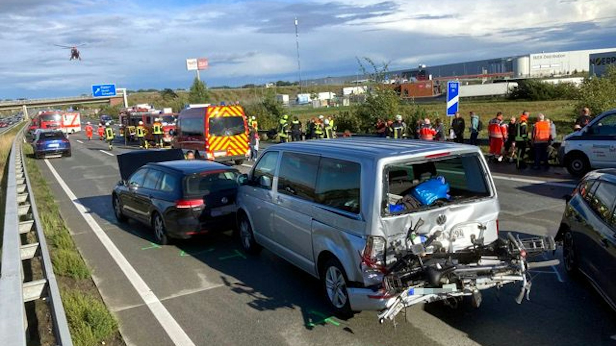 Unfallautos stehen auf der Autobahn A1. Im Hintergrund landet ein Hubschrauber.