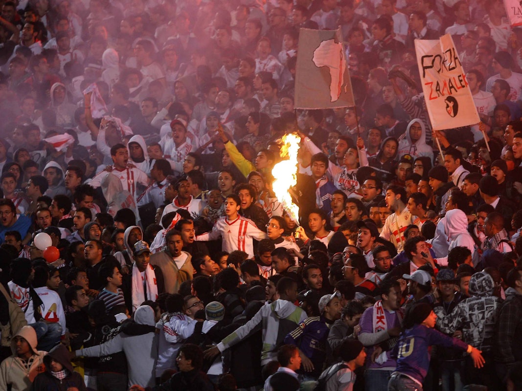 Fußball-Fans bedrängen sich auf den Tribünen und legen Feuer.