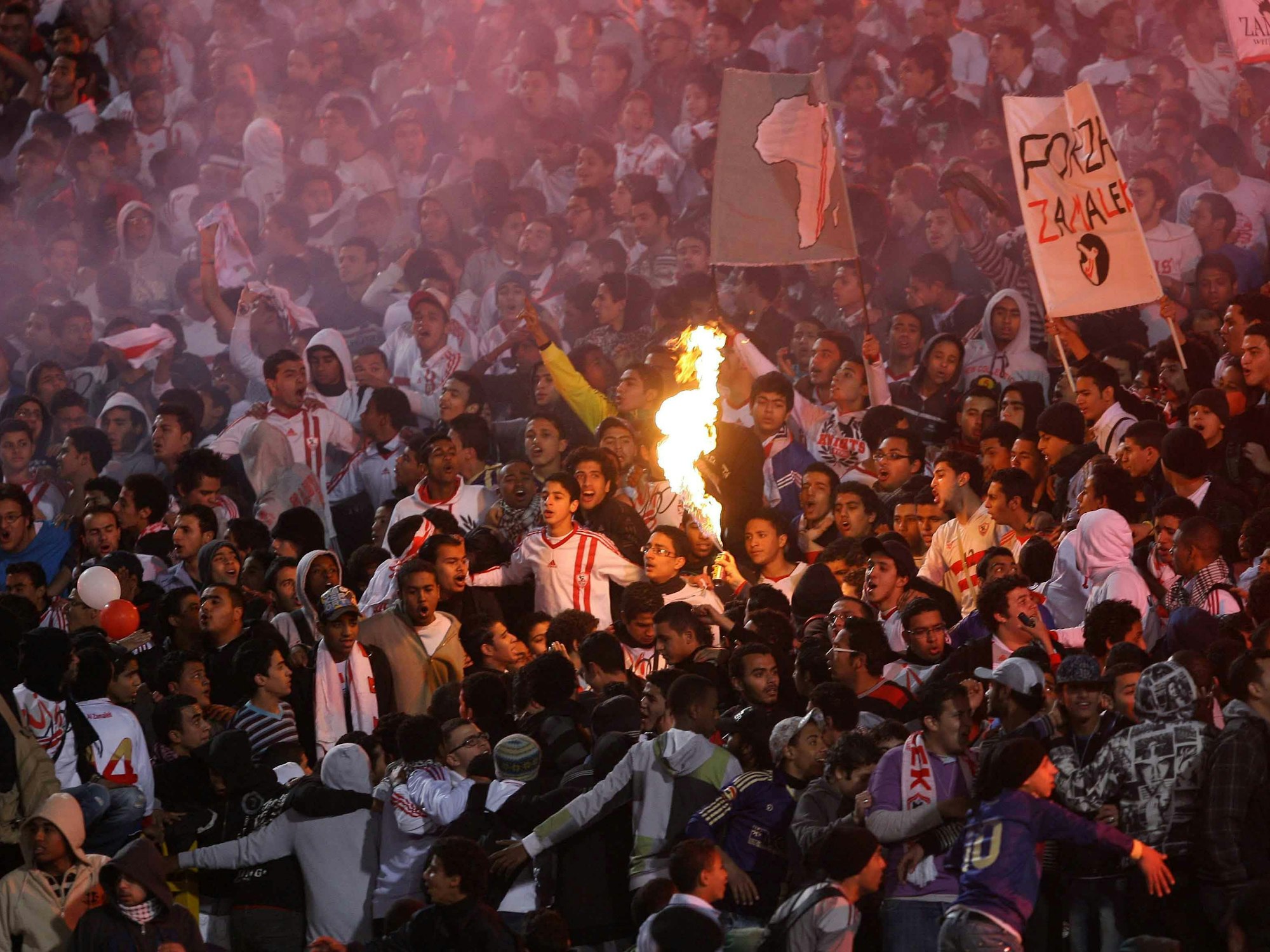Fußball-Fans bedrängen sich auf den Tribünen und legen Feuer.