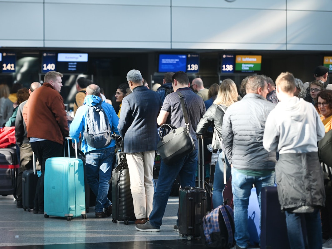 Reisende des Düsseldorfer Flughafens stehen in der Abflughalle an den Schaltern in Schlangen.