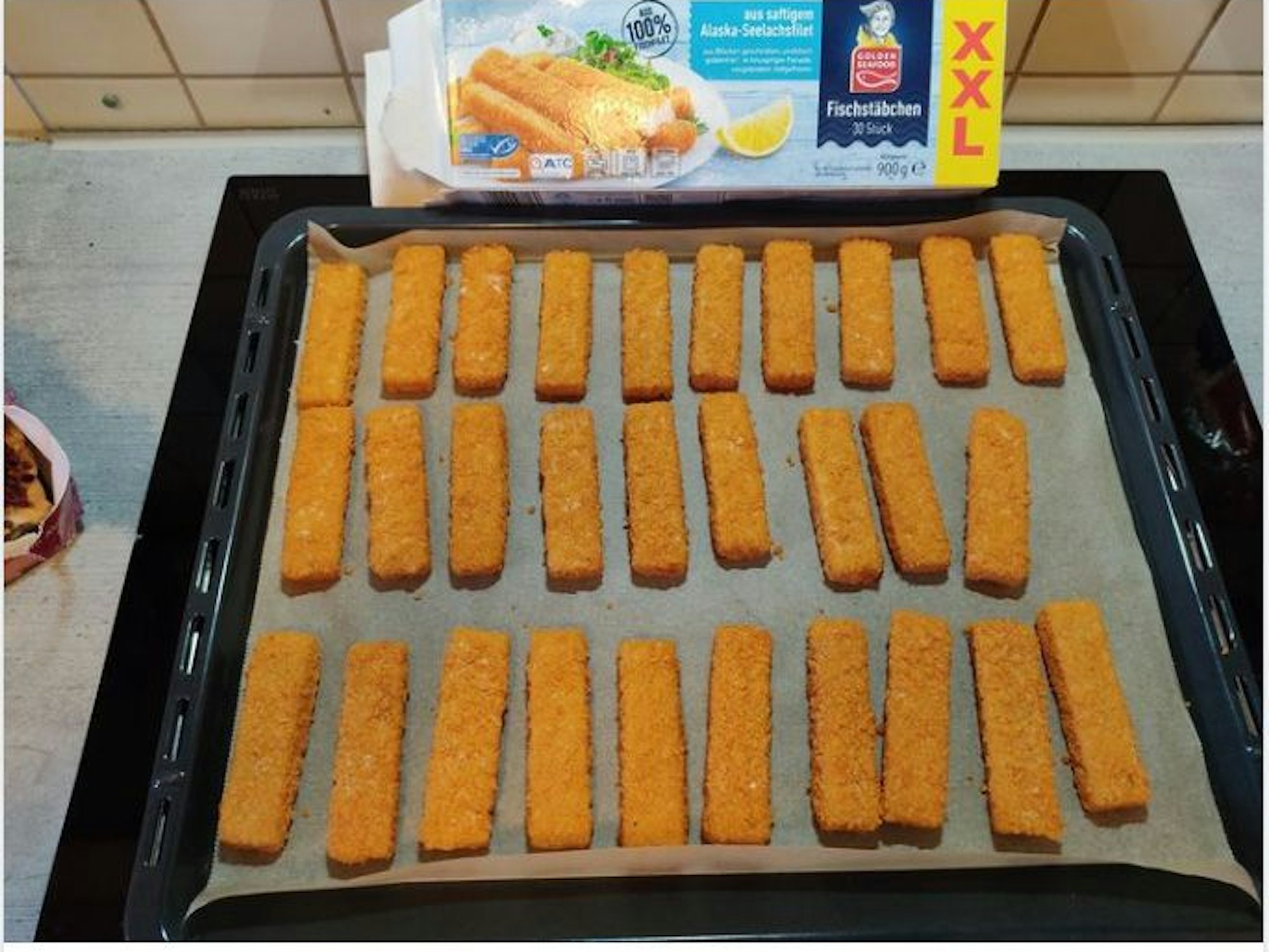 Ein Backblech auf dem Fischstäbchen liegen.