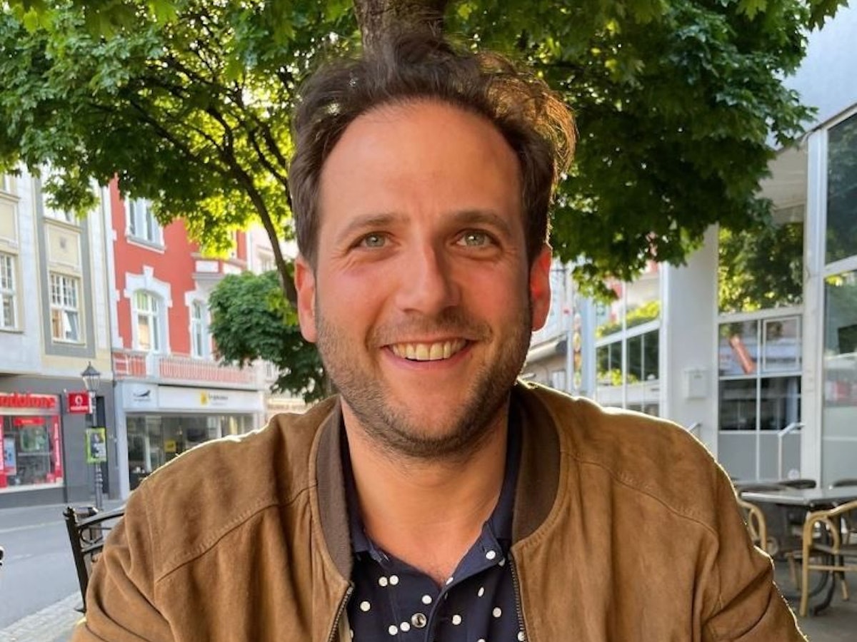 „Bares für Rares“-Händler Julian Schmitz-Avila lächelt bei einem Restaurantbesuch fröhlich in die Kamera.