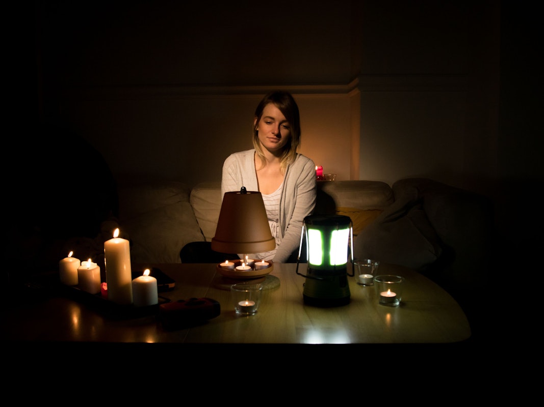 Eine junge Frau beleuchtet ihre Wohnung während eines Stromausfalls mit Kerzen