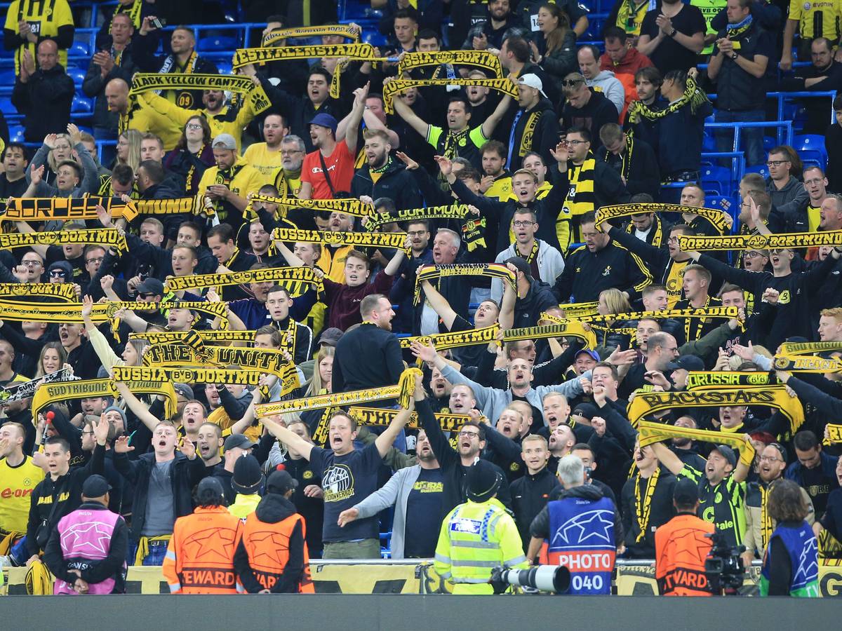 Fans von Borussia Dortmund halten auf der Tribüne ihre Fanschals hoch.