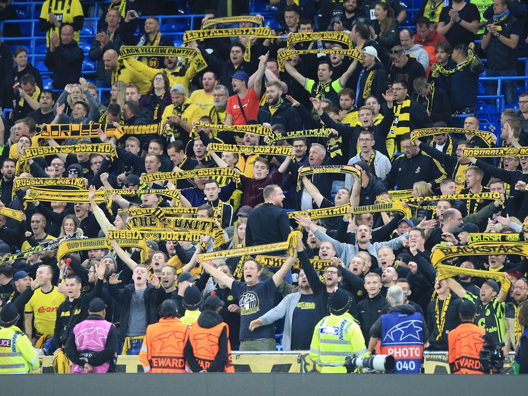 Fans von Borussia Dortmund halten auf der Tribüne ihre Fanschals hoch.