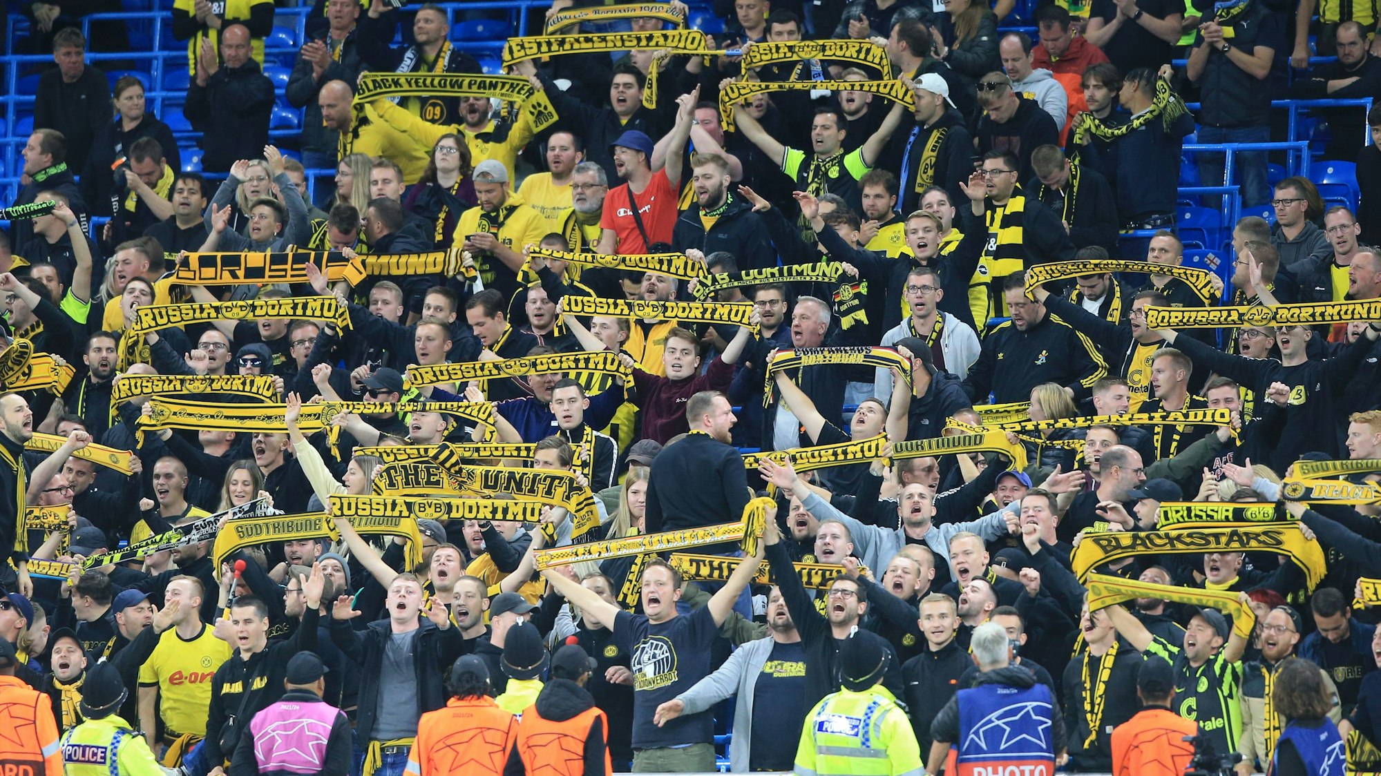 Fans von Borussia Dortmund halten auf der Tribüne ihre Fanschals hoch.
