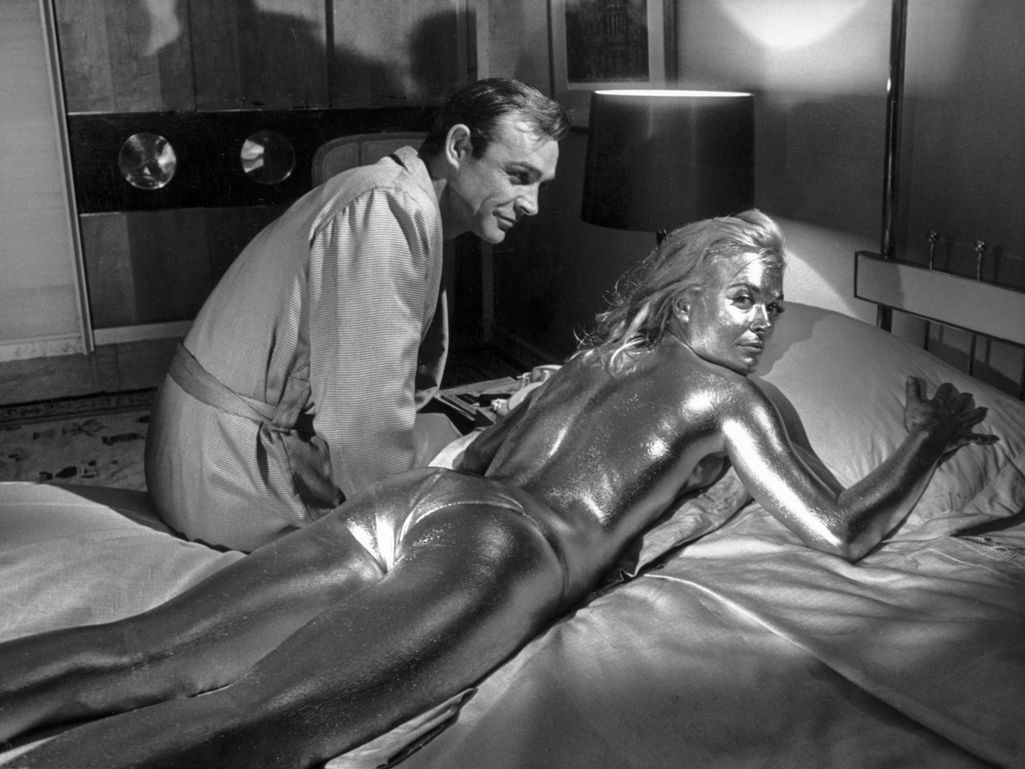Der Schauspieler Sean Connery in der Rolle des James Bond und die goldüberzogene Shirley Eaton, aufgenommen während der Dreharbeiten zum James-Bond-Film "Goldfinger" im Jahre 1964.