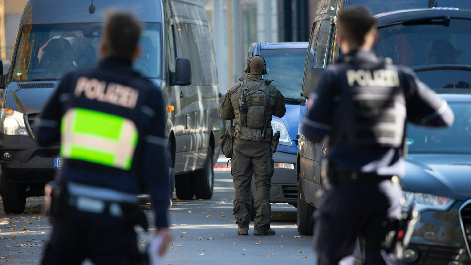 Beamte eines Spezialeinsatzkommandos stehen vor einem Mehrparteienhaus.