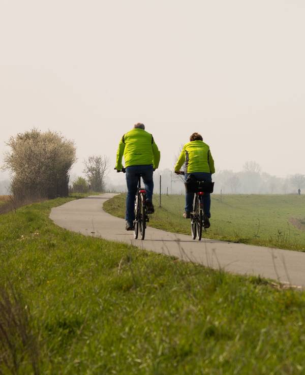 Ein Fahrradfahrer und eine Fahrradfahrerin fahren auf dem Weser-Radweg bei Höxter.