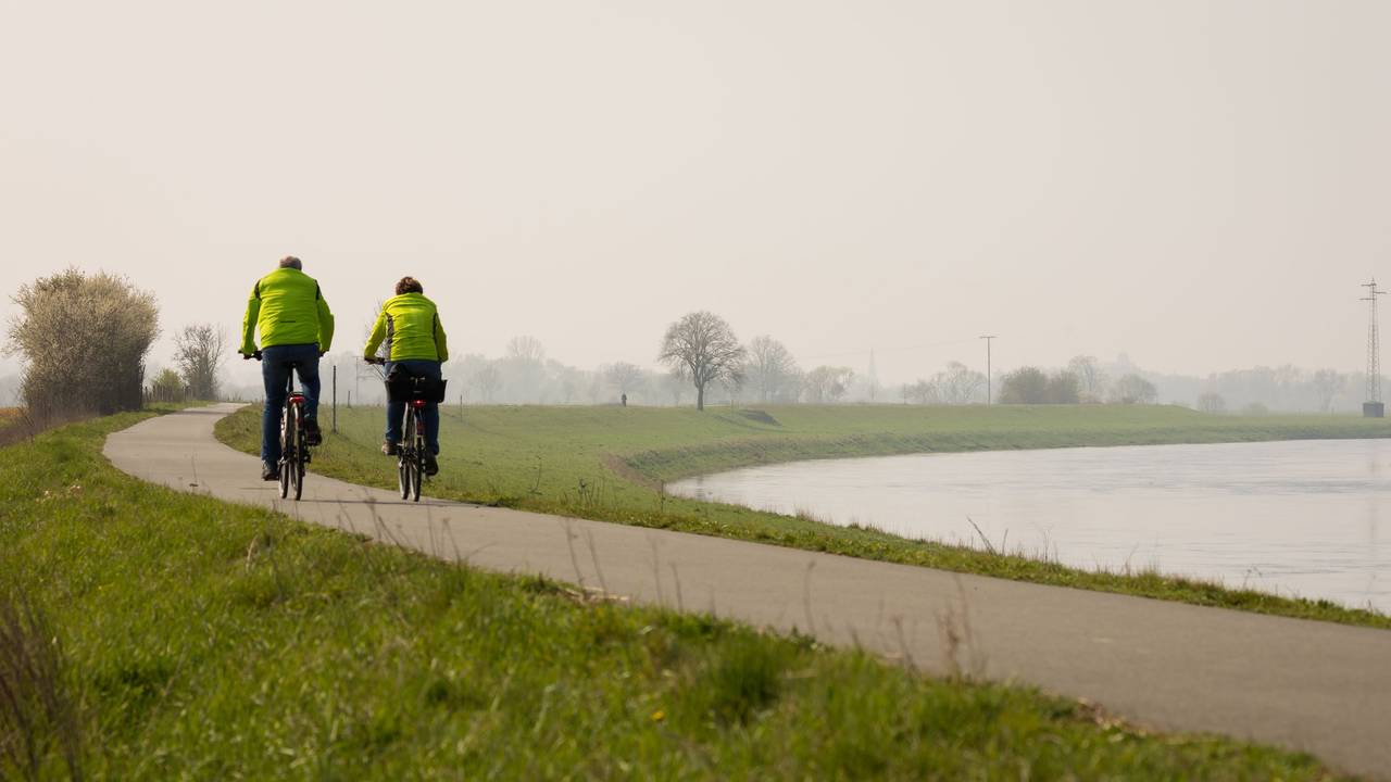 Ein Fahrradfahrer und eine Fahrradfahrerin fahren auf dem Weser-Radweg bei Höxter.