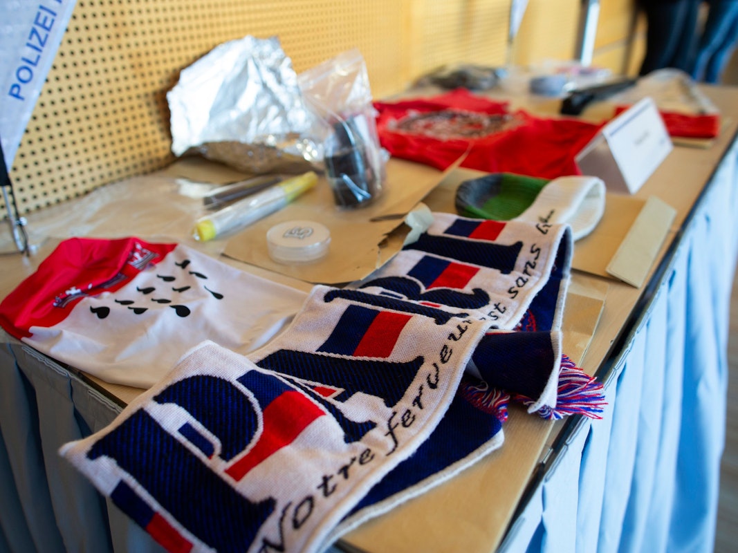 Sichergestellte Gegenstände liegen während einer Pressekonferenz im Polizeipräsidium Köln zum Ergebnis der Hausdurchsuchungen im Zusammenhang mit den Ausschreitungen und Durchsuchungen beim Conference-League-Spiel des 1. FC Köln in Nizza zur Ansicht aus.