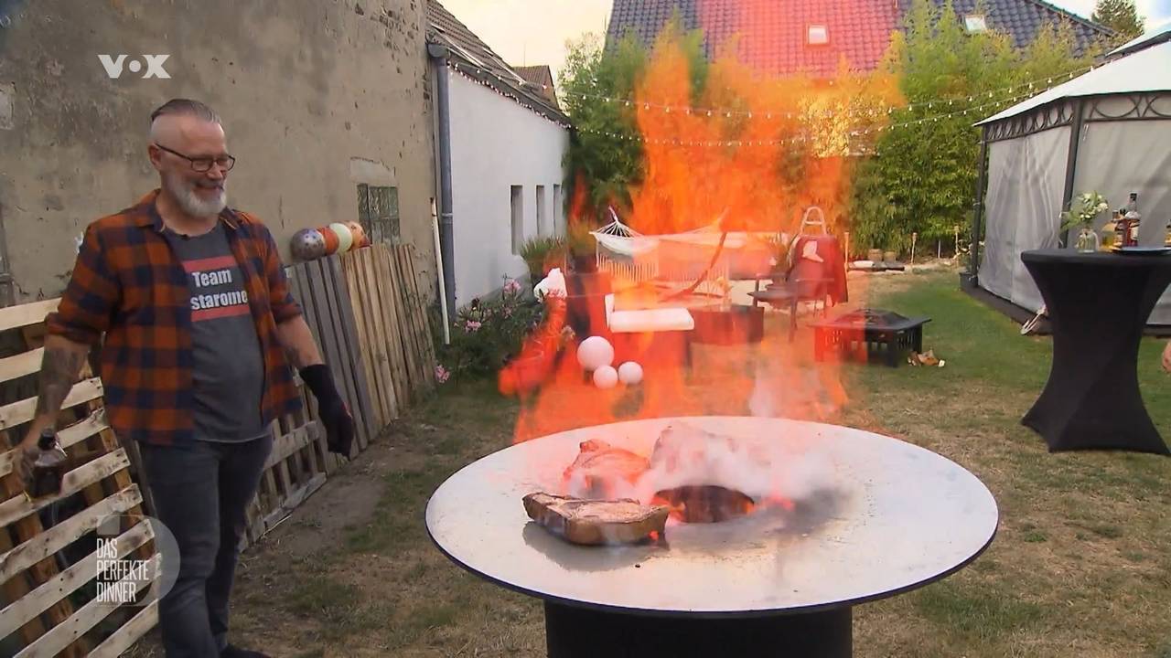 „Das perfekte Dinner“-Kandidat Olli lässt die Flammen in der Feuertonne tanzen, denn für ihn ist Grillen „Rock’n’Roll“.