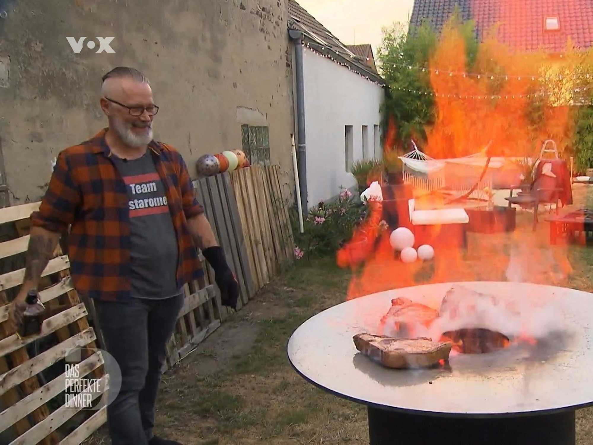 „Das perfekte Dinner“-Kandidat Olli lässt die Flammen in der Feuertonne tanzen, denn für ihn ist Grillen „Rock’n’Roll“.
