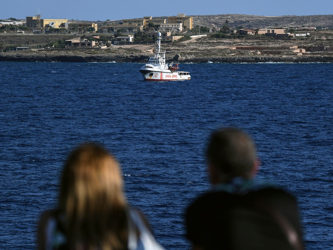 Zwei Menschen auf einer Fähre schauen auf das Rettungsschiff „Open Arms“ der Hilfsorganisation Proactiva. Die Aufnahme dient hier als Symbolfoto.