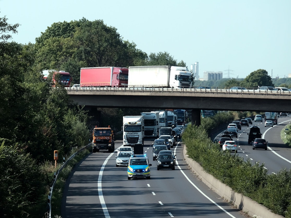 Ein Polizeiauto fährt über die A57. Dahinter fahren weitere Autos.